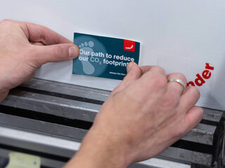 Recycled Zehnder Product two hands sticking a sticker to zehnder recycled product