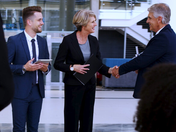 two men and one women in suits talking  to each other 